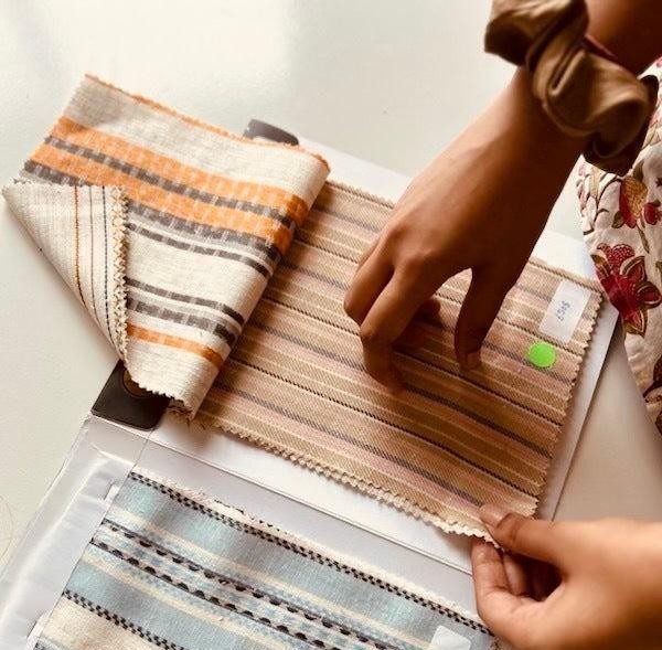 Fabric swatches being evaluated by a designer for wholesale textile sourcing and custom fashion production.